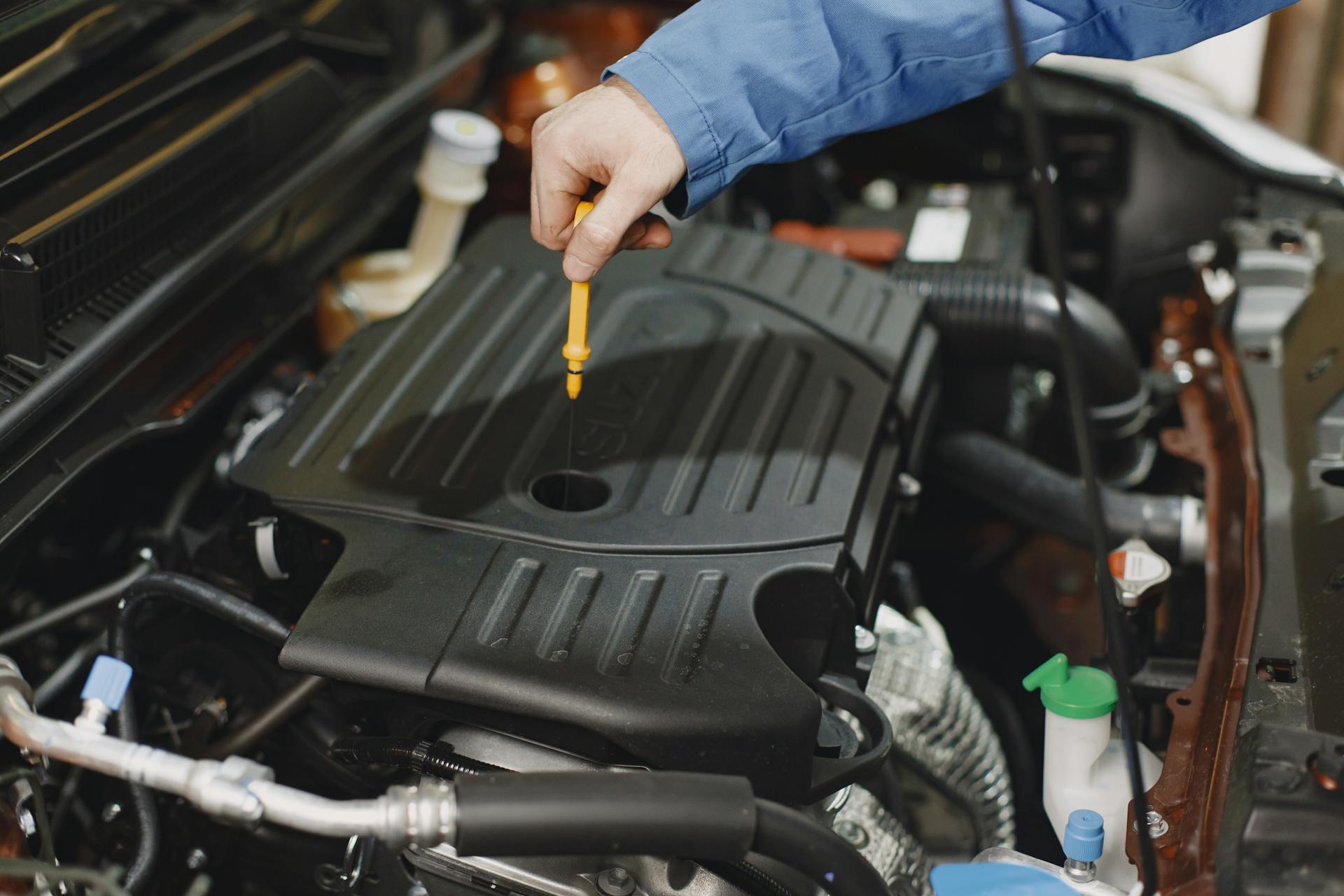 Automobilių mechanikas servise atlieka tepalų keitimą ir techninę apžiūrą